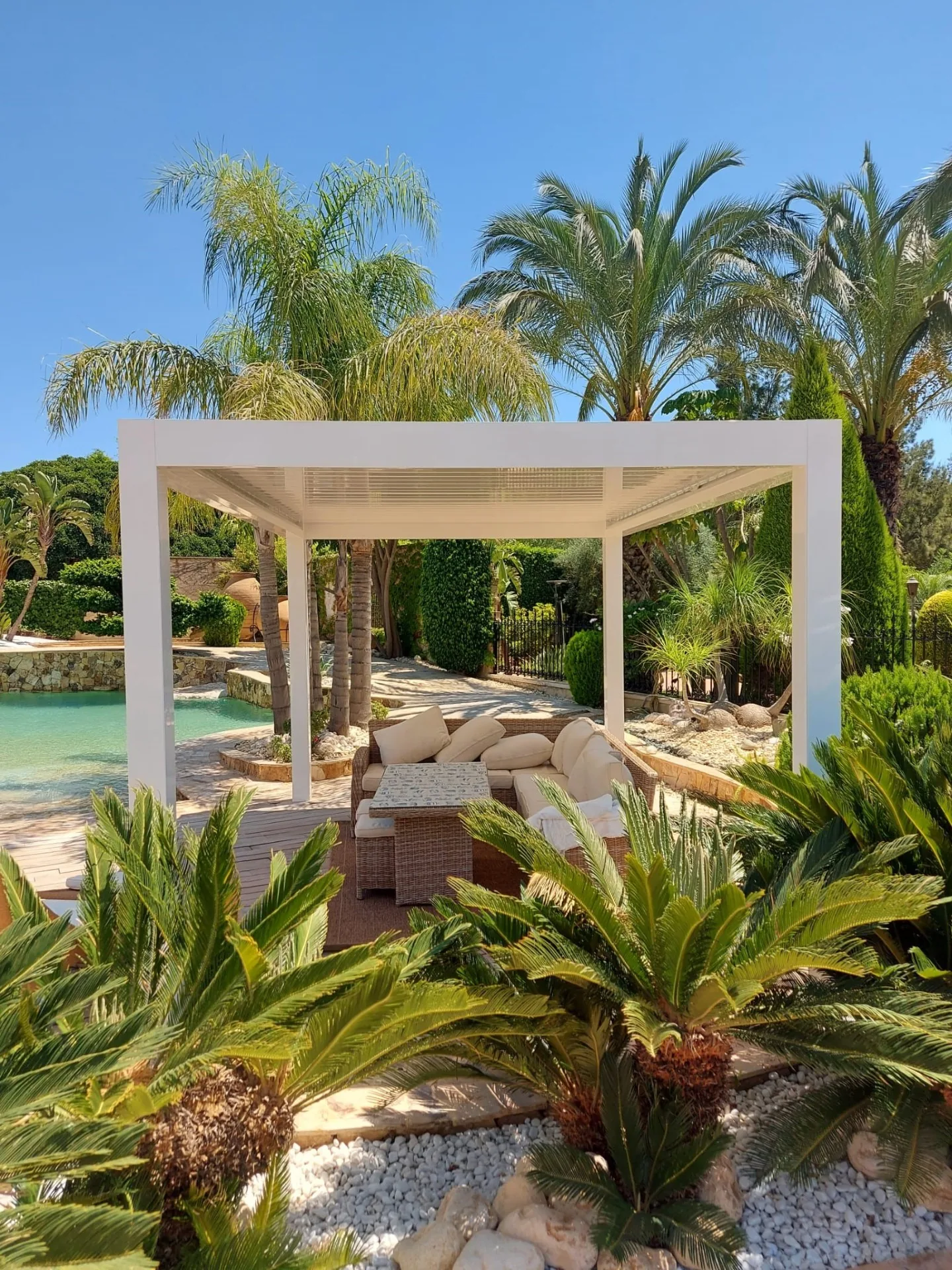 Pérgola blanca en una zona de descanso rodeada de vegetación