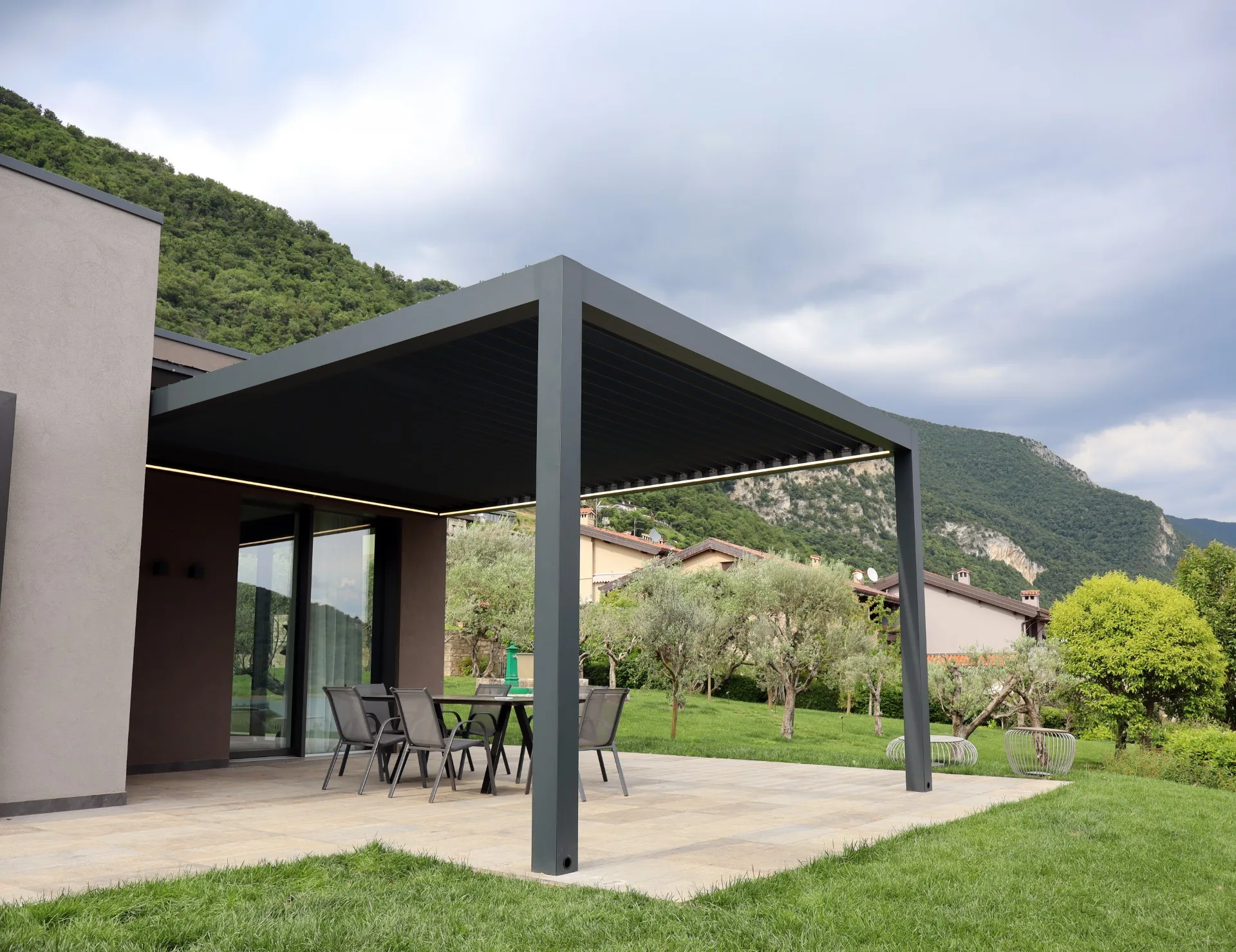 Pérgola bioclimática oscura integrada en el jardín de una vivienda