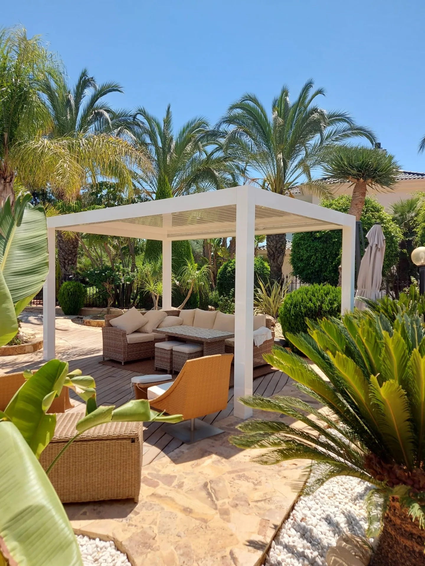 Zona de descanso bajo una pérgola blanca junto a la piscina